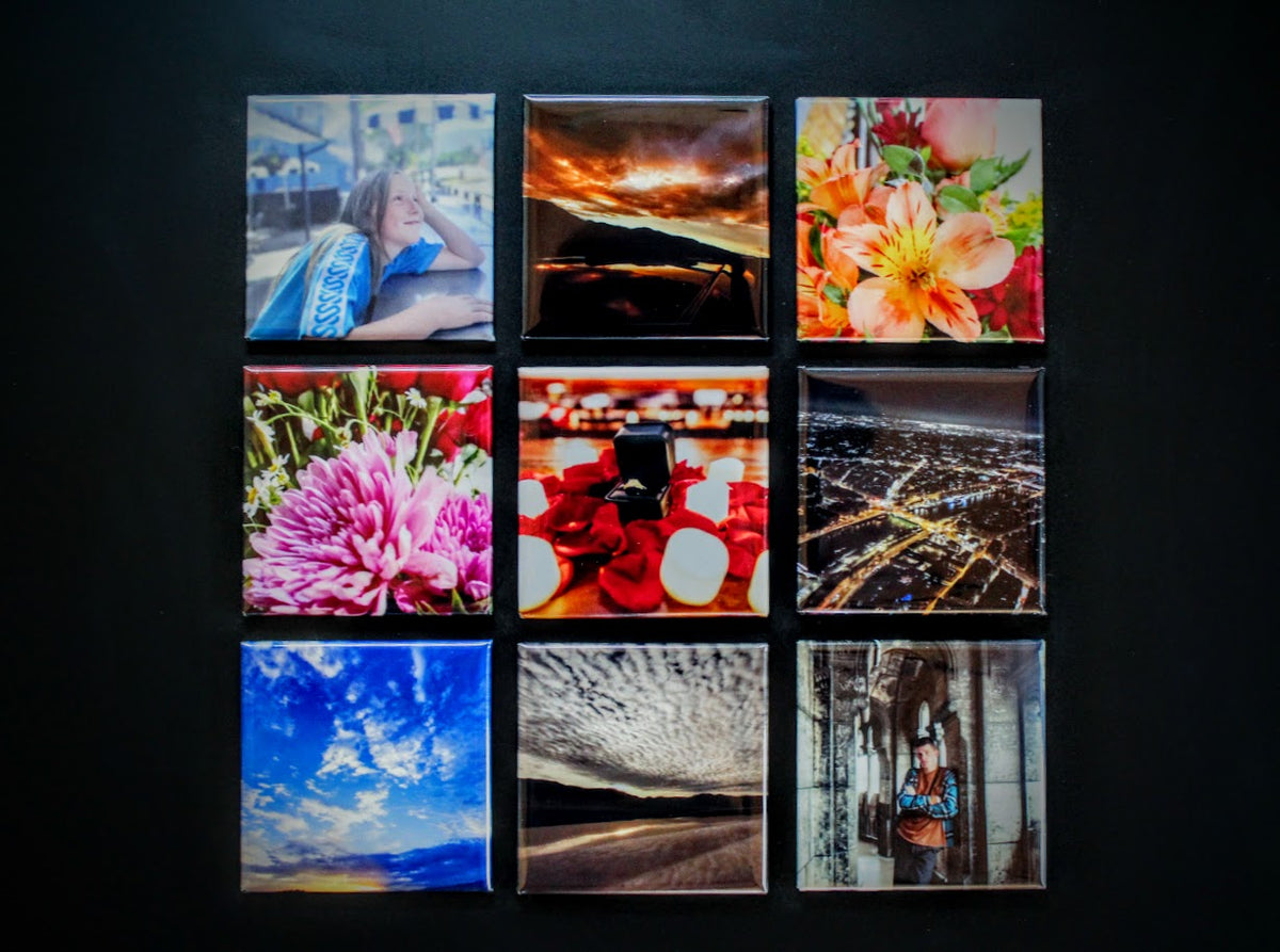 A 3x3 grid of nine square photographic prints mounted on a dark wall. The prints feature diverse scenes and close-ups, including flowers, a city night view, a blue sky, and abstract landscapes.